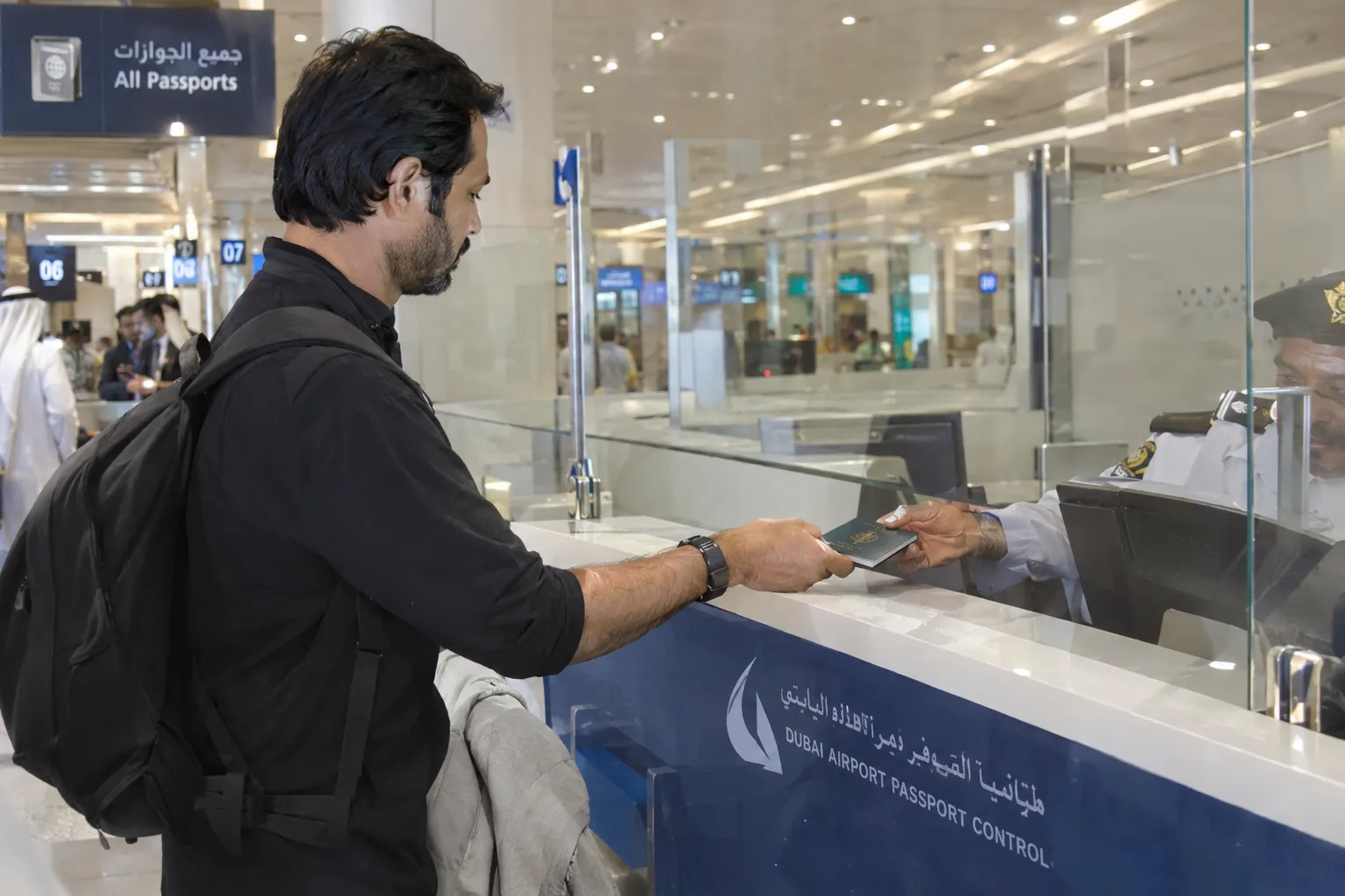 Traveller handing a passport across a Dubai airport immigration counter